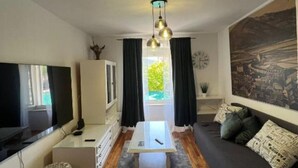 A modern living room with a sofa, TV, and a dining area. - Ston Heritage Apartment with City view (Ston)