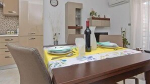 Un comedor con una mesa dispuesta para dos personas, una botella de vino y un reloj en la pared.