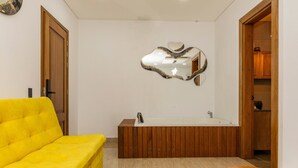 A bathroom with a wooden bathtub, a yellow sofa, and a mirror with a heart-shaped frame. - Ecohotel Dubai Del Oriente (El Penol)