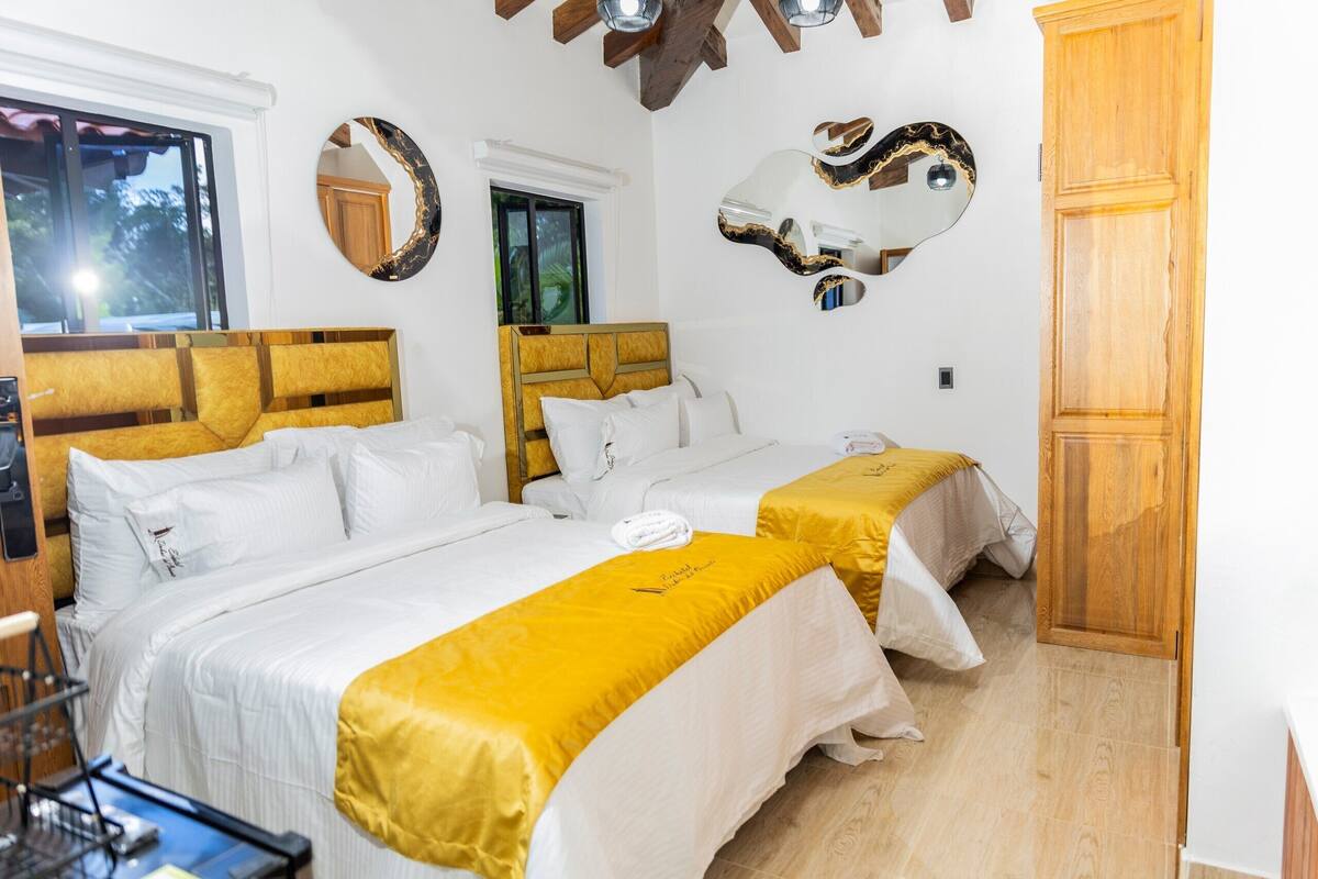 Een hotelkamer met twee bedden, een houten hoofdbord, een spiegel en een houten deur.