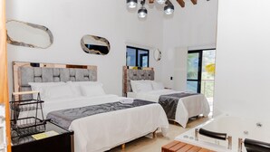 A hotel room with two beds, a wooden bench, a bathtub, and a large mirror. - Ecohotel Dubai Del Oriente (El Penol)