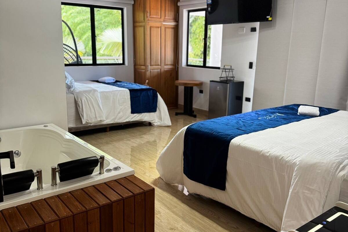 Een kamer met twee bedden, een houten kast, een klein tafeltje, een televisie en een bad.