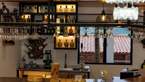 A bar area with shelves of liquor bottles, a wine rack, and a view of a building through a window. - Ecohotel Dubai Del Oriente (El Penol)