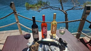 Ein Tisch mit einem Fischteller, drei Weinflaschen und einem Weinglas.