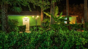 Un bâtiment à la façade verdoyante, avec une porte blanche et un lampadaire allumé.