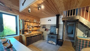 Una cucina rustica con travi in legno, un camino in pietra e una finestra che si affaccia sul verde.