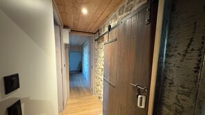 Un corridoio con pavimento in legno, parete in pietra e porta in legno con maniglia in metallo.