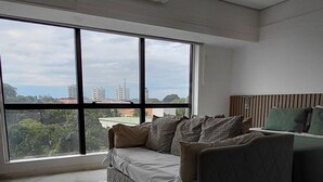 Een moderne woonkamer met een groot raam, een bank en een bed.