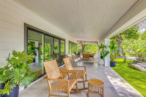 Un espace extérieur aménagé avec des meubles en osier, un sol en béton et des plantes en pot, le tout abrité.