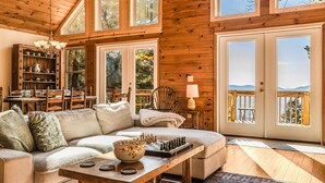 Ein gemütliches Holzhaus-Interieur mit einer Couch, einem Schachbrett und einem Essbereich.