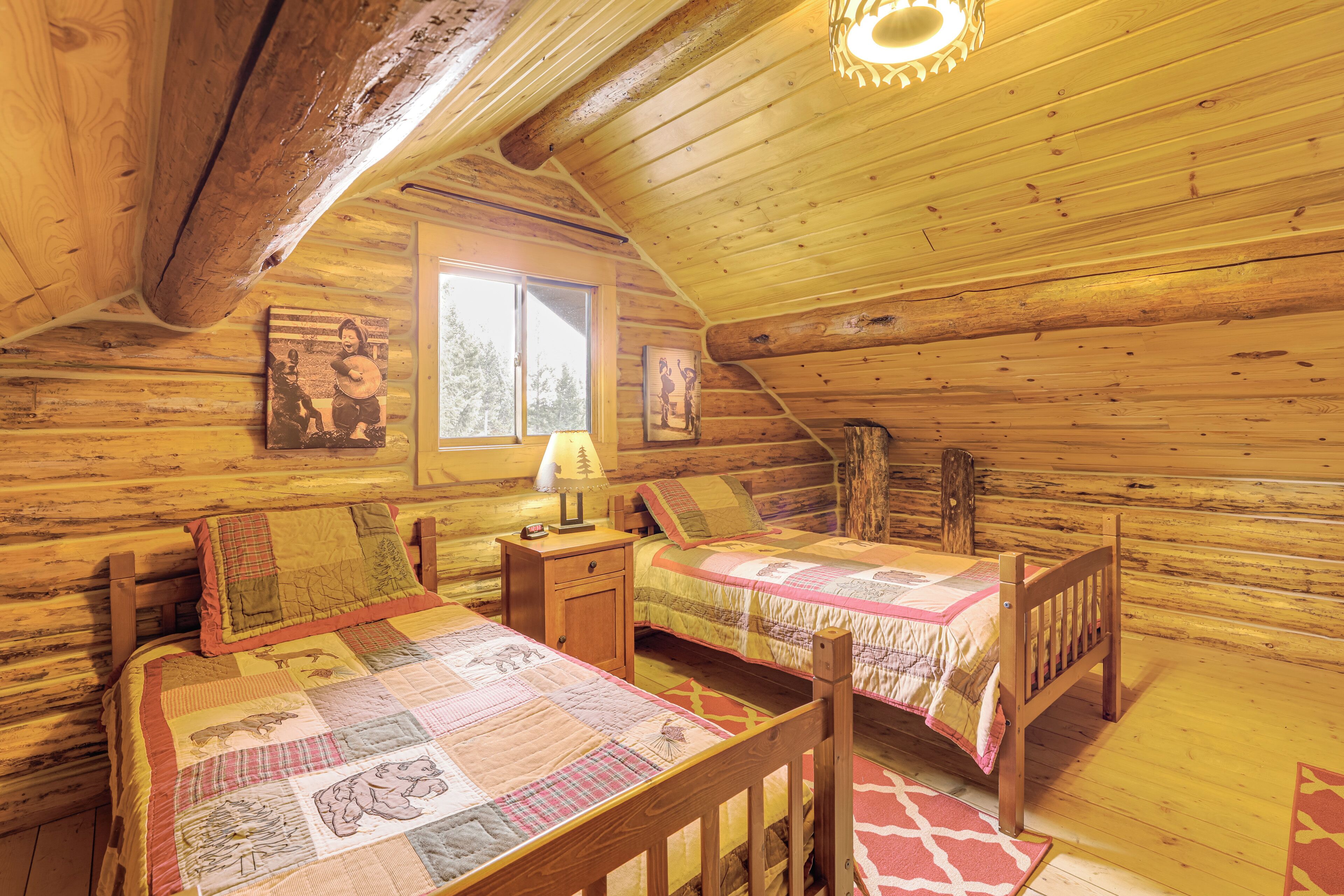 Une chambre dans un chalet en rondins, avec deux lits, une fenêtre et des murs en bois.
