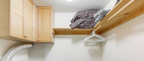 A compact laundry room with a washing machine, wooden cabinets, and a clothes drying rack.