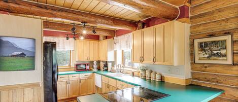 A kitchen with wooden cabinets, a turquoise countertop, a refrigerator, and a microwave.
