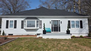 Une maison à deux étages avec un porche à l’avant, une baie vitrée et une porte d’entrée noire.