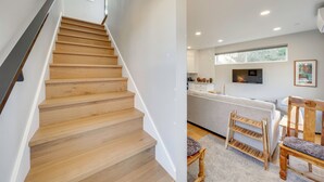 Eine Treppe führt zu einer modernen Küche mit weißen Schränken und einem grauen Sofa.