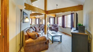 A spacious living room with a leather sofa, a coffee table, and a television on a stand.