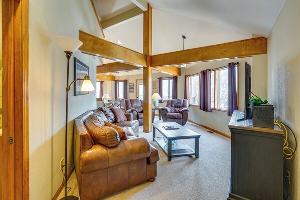 A spacious living room with a leather sofa, a coffee table, and a television on a stand.
