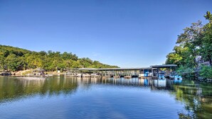 A calm lake with a dock and boats, surrounded by trees and hills.