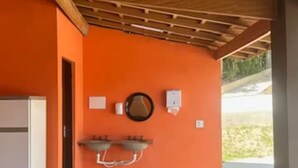 Un espacio exterior techado con suelo de baldosas, techo de madera y pared naranja.