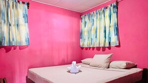 A room with a bed, pillows, curtains, and a wooden chair. - Sabores de mi Tierra (Popoyo)