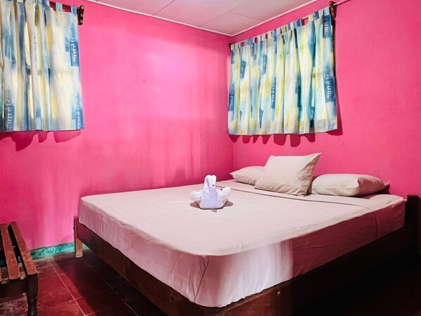 Una habitación con cama, almohadas, cortinas y una silla de madera.