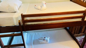A bunk bed with a wooden frame, white bedding, and two plush toys on the top bunk. - Sabores de mi Tierra (Popoyo)