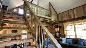 A wooden staircase with a railing, a ceiling fan, and a sofa in a cabin-like interior.
