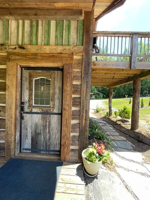 Eine Holzhütte mit einer großen Tür, einer überdachten Veranda und einem Blumentopf.