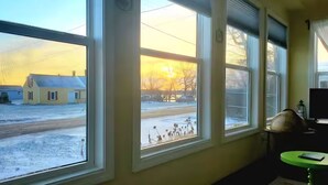 A room with large windows, a television, and a small table. - Mermaid's Mini Mansion (Eastport)