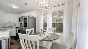 A modern kitchen with white cabinetry, a stainless steel refrigerator, and a dining table with chairs. - Chateau Elan Family Home Retreat Fast WiFi Sleeps 15 (Hoschton)