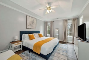 A bedroom with a bed, a nightstand, a TV, a ceiling fan, and a window with curtains. - Chateau Elan Family Home Retreat Fast WiFi Sleeps 10 (Hoschton)