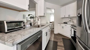 A modern kitchen with white cabinets, stainless steel appliances, and a marble countertop. - Chateau Elan Family Home Retreat Fast WiFi Sleeps 15 (Hoschton)