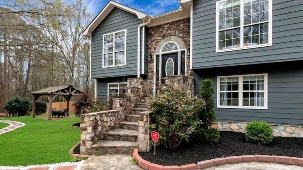 A two-story house with a stone staircase, a covered patio, and a well-maintained lawn. - Chateau Elan Family Home Retreat Fast WiFi Sleeps 15 (Hoschton)