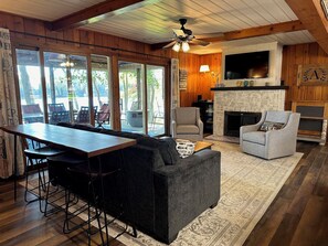 A cozy living room with a fireplace, a bar area, and large windows offering a view of the outdoors. - (Nisswa)