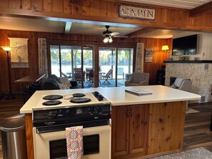 A cabin interior with a kitchen island, dining area, and a large TV. - (Nisswa)