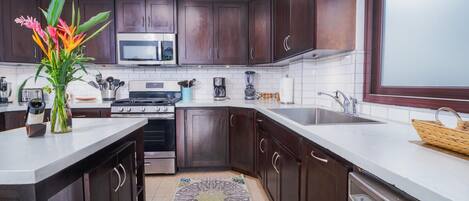 Una cocina moderna con armarios de madera oscura, estufa de acero inoxidable, microondas y lavavajillas.