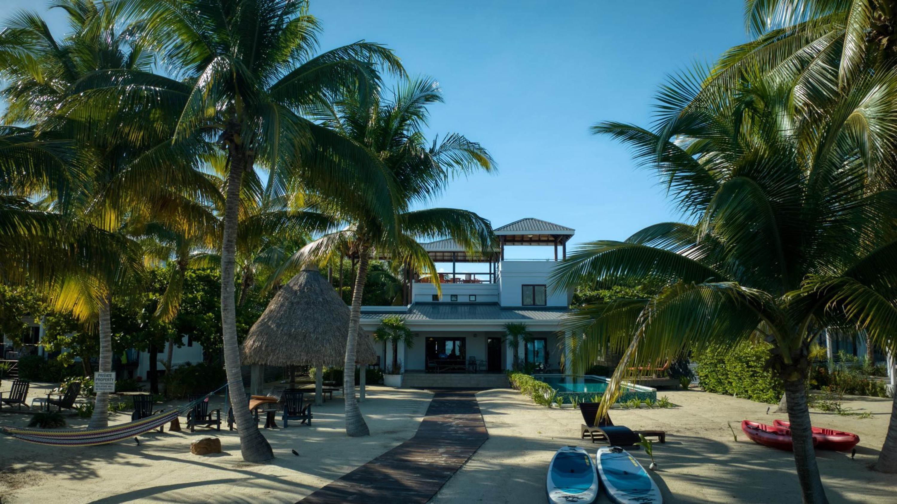Un resort con piscina, palmeras y una estructura de techo de paja.