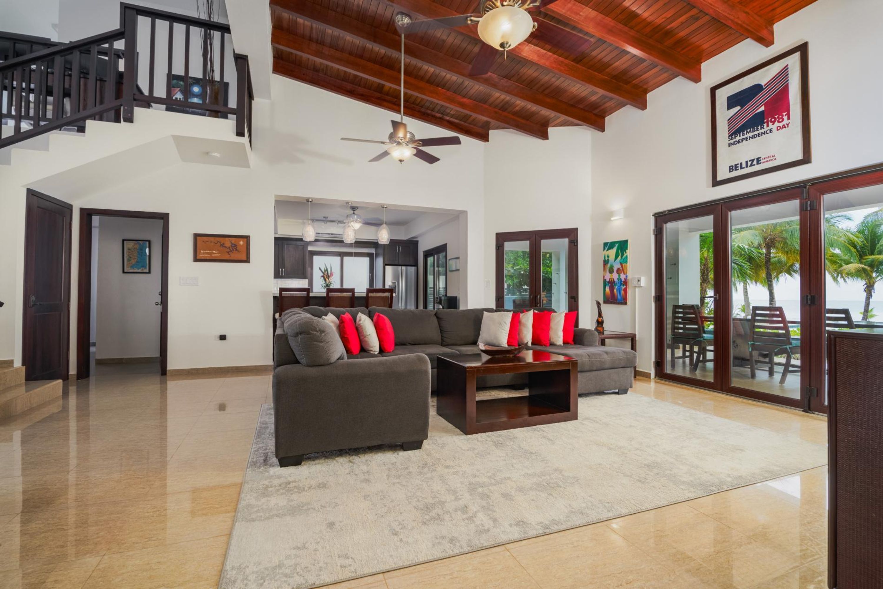 A spacious living room with a high ceiling, a staircase, and a view of the outdoors.