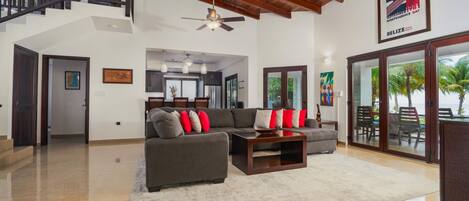 A spacious living room with a high ceiling, a staircase, and a view of the outdoors.