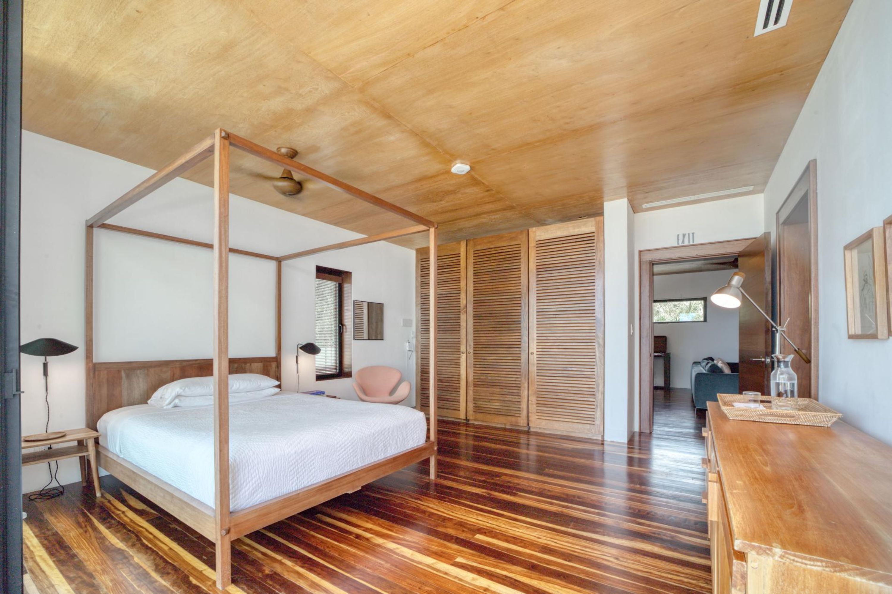 A four-poster bed in a room with wooden flooring and a wooden ceiling.