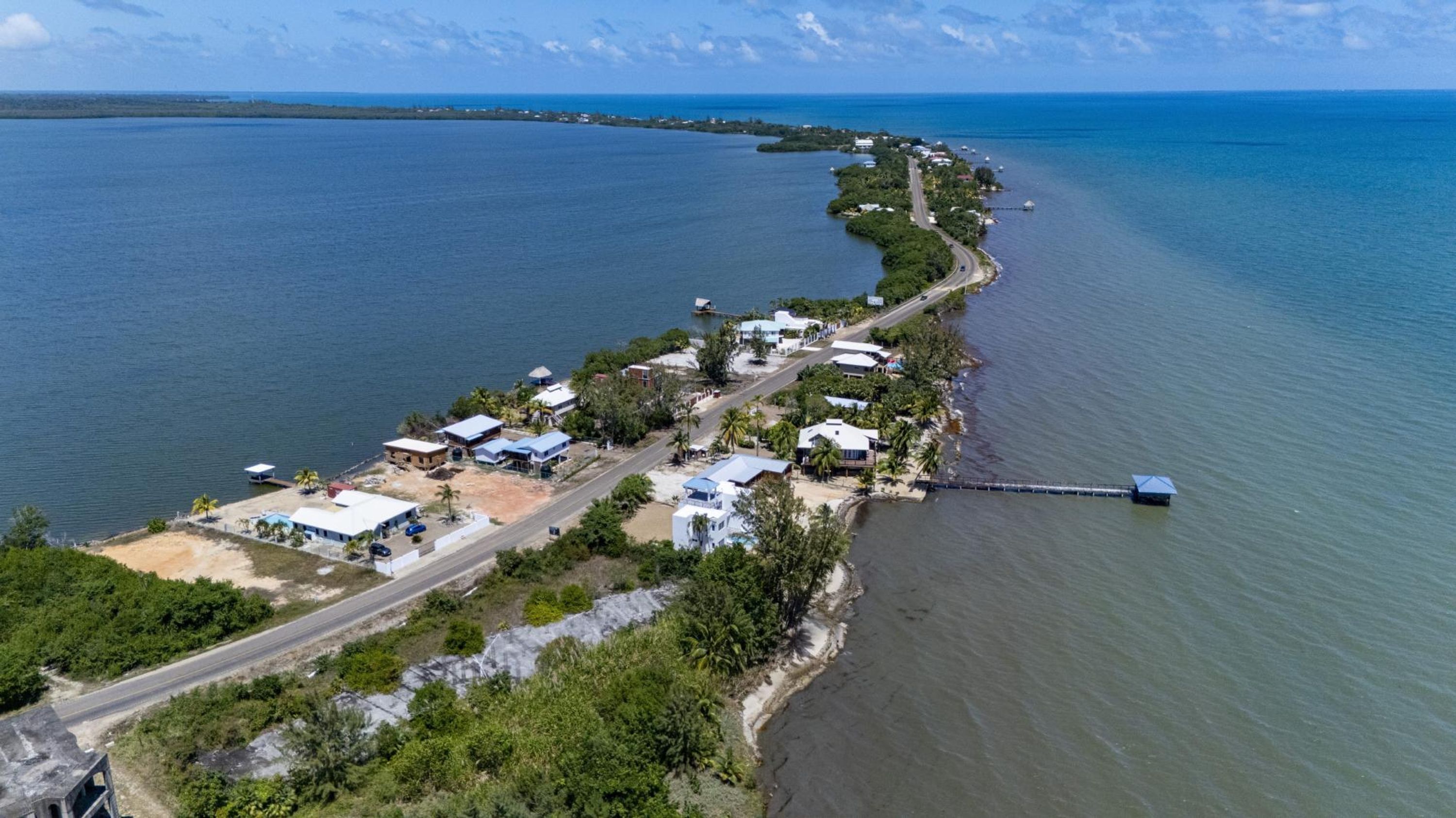 Une vue aérienne d’une zone côtière, avec une route menant à un ensemble de bâtiments situés le long de la côte.
