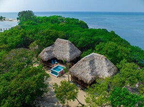A tropical resort with thatched-roof huts, a swimming pool, and lush greenery.