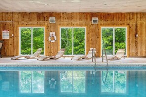 A wooden-paneled indoor pool with four lounge chairs and large windows. - Paradise Pocono - Indoor Pool Poconos Retreat with Arcade Sleeps 16 (Lake Ariel)