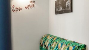 A small, cozy room with a single bed, a wall-mounted light, a framed picture, and a potted plant. - Luxury Vatican Rooms (Rome)