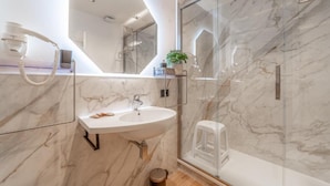 A modern bathroom with a marble sink, a hairdryer, and a glass shower enclosure. - Luxury Vatican Rooms (Rome)