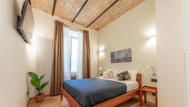 A bedroom with a wooden bed, a potted plant, a radiator, and a painting on the wall. - Luxury Vatican Rooms (Rome)