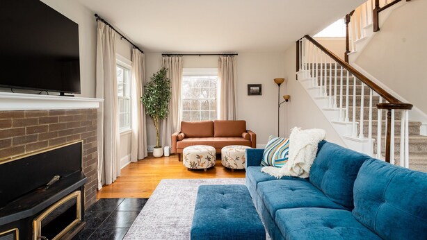 Un salon avec une cheminée, un canapé bleu, un canapé marron et un escalier.