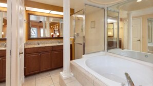 Une salle de bain dotée d’une grande baignoire, d’une douche à parois de verre et d’un meuble-lavabo double avec un miroir.