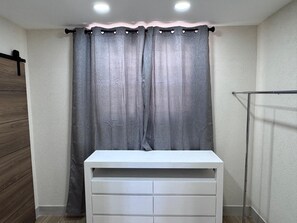 Un baño con tocador blanco, cortinas grises y suelo de madera.