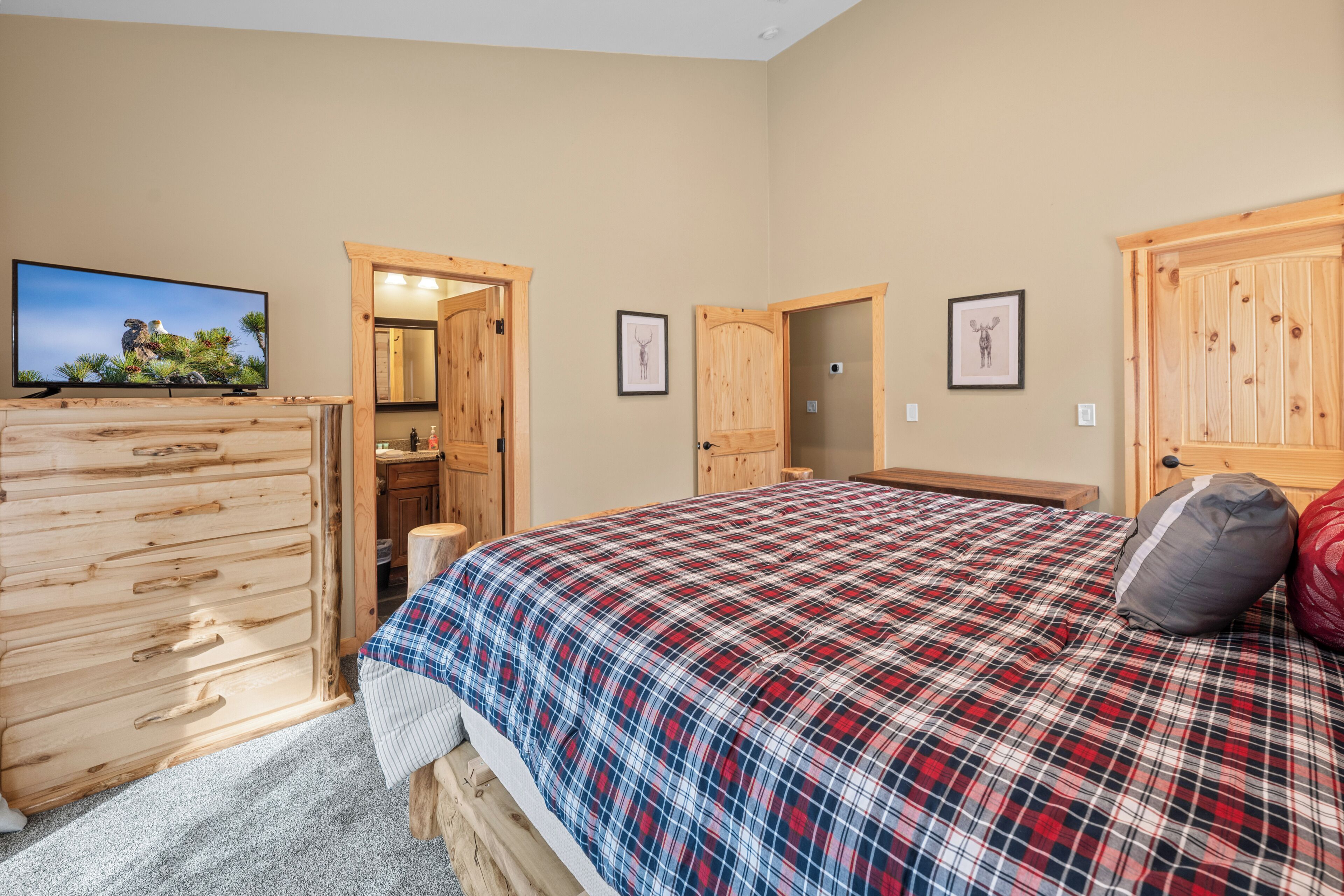 A bedroom with a plaid bedspread, wooden wardrobe, and a television on a stand.